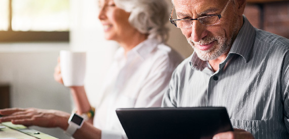 Elderly man checking his account on his tablet.