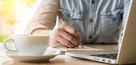 Man writing down research in his notepad.